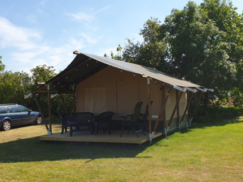 Tienda safari en Camping Eefting, Países Bajos, con porche, sillas exteriores y árboles de fondo.