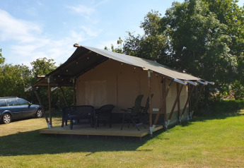 Tenda safari al Camping Eefting nei Paesi Bassi con veranda, sedie esterne e alberi verdi dietro.