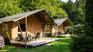 Tiendas safari con terrazas de madera en Camping Bockenauer Schweiz en Alemania, rodeadas de vegetación y árboles.