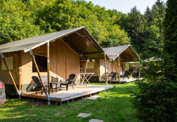 Tiendas safari con terrazas de madera en Camping Bockenauer Schweiz en Alemania, rodeadas de vegetación y árboles.