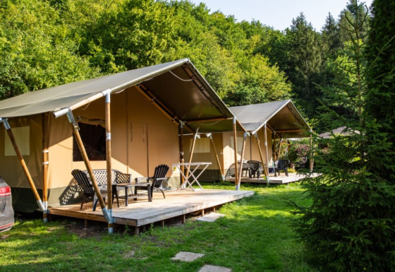 Tiendas safari con terrazas de madera en Camping Bockenauer Schweiz en Alemania, rodeadas de vegetación y árboles.