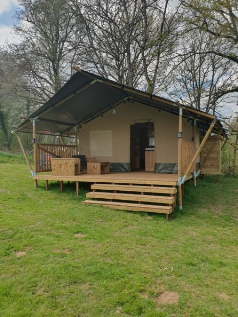 Tenda safari al Moulin du Pommier Glamping & Camping in Francia, con veranda in legno e prato verde.