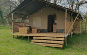 Safari-Zelt bei Moulin du Pommier Glamping & Camping in Frankreich mit Holzterrasse und Garten.