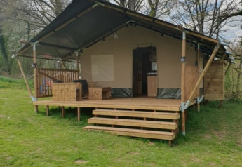 Safari-Zelt bei Moulin du Pommier Glamping & Camping in Frankreich mit Holzterrasse und Garten.