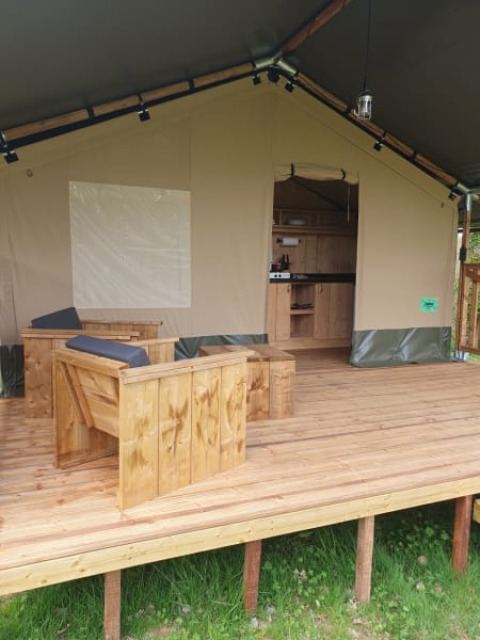 Tienda safari con terraza de madera y zona de estar en Moulin du Pommier Glamping & Camping en Francia.