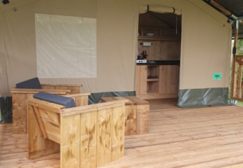 Tienda safari con terraza de madera y zona de estar en Moulin du Pommier Glamping & Camping en Francia.