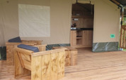 Safari-Zelt mit Holzveranda und Sitzgelegenheiten bei Moulin du Pommier Glamping & Camping in Frankreich.