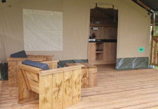 Safaritent met houten terras en zitruimte bij Moulin du Pommier Glamping & Camping in Frankrijk.