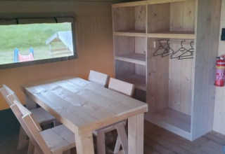 Vista interna di una tenda safari con mobili in legno rustico e armadio al Moulin du Pommier Glamping in Francia.