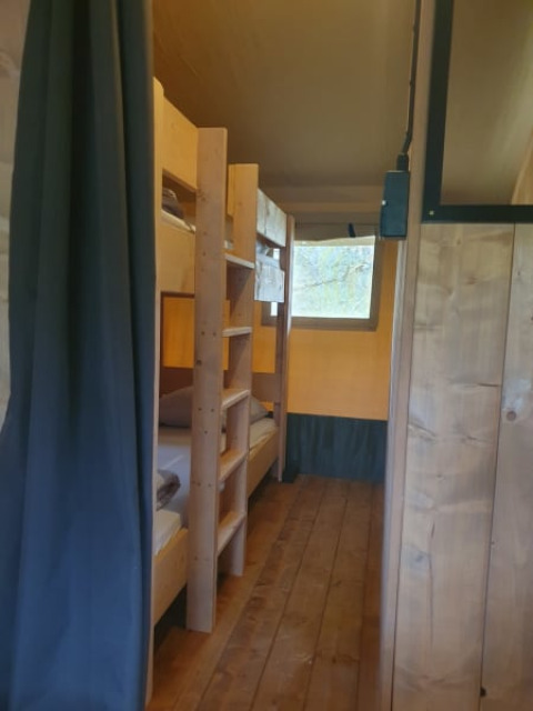 Interno di una tenda safari con letti a castello e pavimento in legno al Moulin du Pommier Glamping & Camping in Francia.