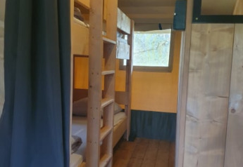 Vista interior de una tienda safari con literas y suelo de madera en Moulin du Pommier Glamping & Camping en Francia.
