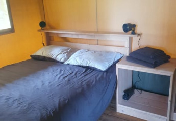 Interior view of a bedroom in a safari tent at Moulin du Pommier Glamping & Camping in France.