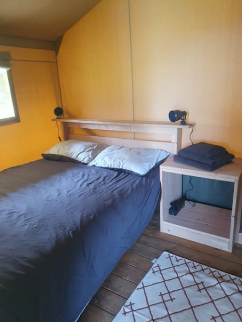 Interior view of a bedroom in a safari tent at Moulin du Pommier Glamping & Camping in France.