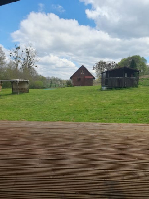 Vista dalla terrazza di una tenda safari a Moulin du Pommier Glamping & Camping su prato e casette.