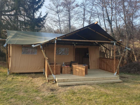 Tienda safari con terraza de madera y muebles al aire libre en Moulin du Pommier Glamping & Camping en Francia.