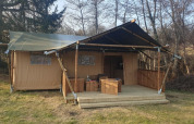 Tienda safari con terraza de madera y muebles al aire libre en Moulin du Pommier Glamping & Camping en Francia.