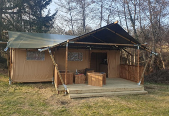 Tienda safari con terraza de madera y muebles al aire libre en Moulin du Pommier Glamping & Camping en Francia.