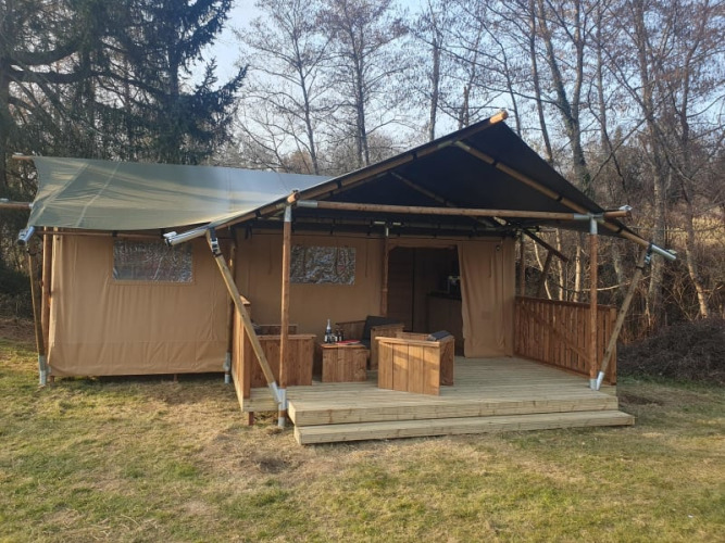 Safari-Zelt mit Holzterrasse und Sitzgelegenheiten bei Moulin du Pommier Glamping & Camping in Frankreich.
