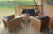 Gemütliche Terrasse am Safari-Zelt im Moulin du Pommier Glamping & Camping, mit Holzmöbeln und Wein.