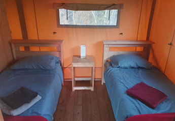 Two single beds with blue bedding in a safari tent at Moulin du Pommier Glamping & Camping in France.
