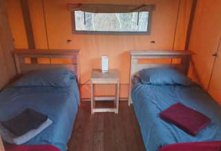 To enkeltsenge ved siden af hinanden i et safari telt med blå sengetøj på Moulin du Pommier Glamping i Frankrig.