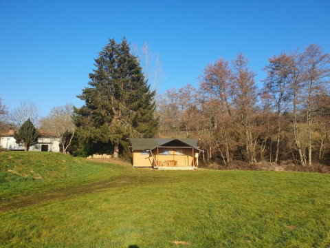 Safari-telt med eget bad på Moulin du Pommier Glamping & Camping i Frankrig på frodig grøn mark under blå himmel.