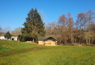 Safaritent met eigen sanitair op Moulin du Pommier Glamping & Camping in Frankrijk, op een groene weide.