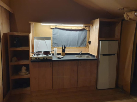 Keukentje in een safaritent bij Moulin du Pommier Glamping & Camping in Frankrijk, met fornuis en frigo.