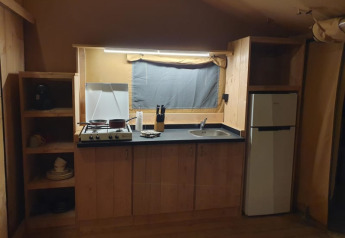 Kitchen inside a safari tent at Moulin du Pommier Glamping & Camping in France with stove, sink, and fridge.