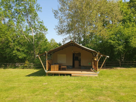 Tienda safari con instalaciones sanitarias en Moulin du Pommier Glamping & Camping, Francia, rodeada de árboles.