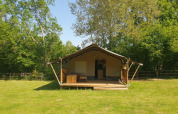 Safari tent with private sanitary at Moulin du Pommier Glamping & Camping, France, surrounded by greenery.