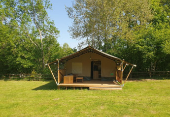 Tienda safari con instalaciones sanitarias en Moulin du Pommier Glamping & Camping, Francia, rodeada de árboles.