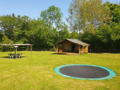 Tenda safari con terrazza privata, trampolino e area salotto al Moulin du Pommier Glamping, Francia.