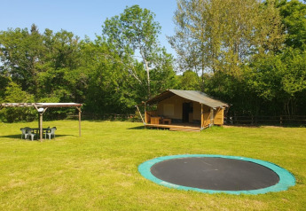 Tenda safari con terrazza privata, trampolino e area salotto al Moulin du Pommier Glamping, Francia.