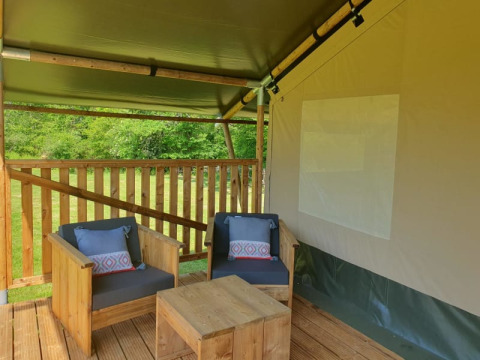 Área de estar con muebles de madera dentro de una tienda safari en Moulin du Pommier Glamping & Camping, Francia.