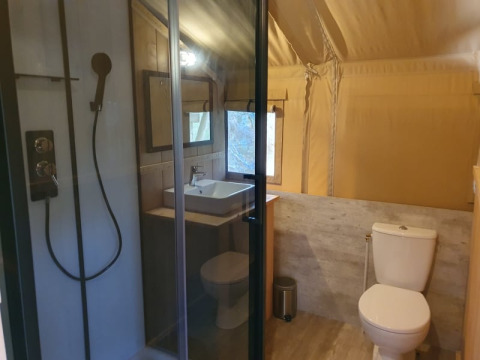 Salle de bain d'une tente safari avec douche, lavabo et toilettes au Moulin du Pommier Glamping & Camping en France.