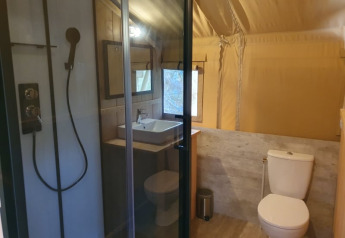 Bathroom of a safari tent featuring shower, sink, and toilet at Moulin du Pommier Glamping & Camping in France.
