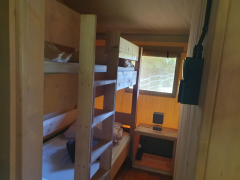 Binnenzicht van safaritent met stapelbedden en bureau bij Moulin du Pommier Glamping & Camping in Frankrijk.