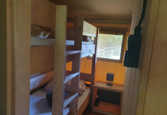 Binnenaanzicht van een safaritent met stapelbedden en bureau bij Moulin du Pommier Glamping & Camping in Frankrijk.