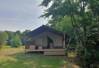 Safari tent with private sanitary facilities at Moulin du Pommier Glamping & Camping in France, among trees.