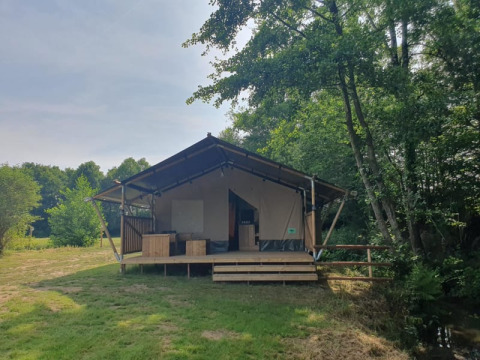 Safari tent with private sanitary facilities at Moulin du Pommier Glamping & Camping in France, among trees.