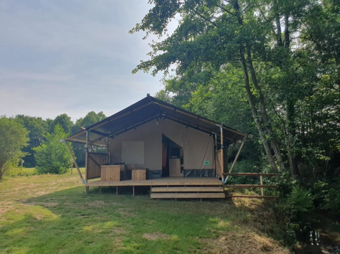 Safari tent with private sanitary facilities at Moulin du Pommier Glamping & Camping in France, among trees.