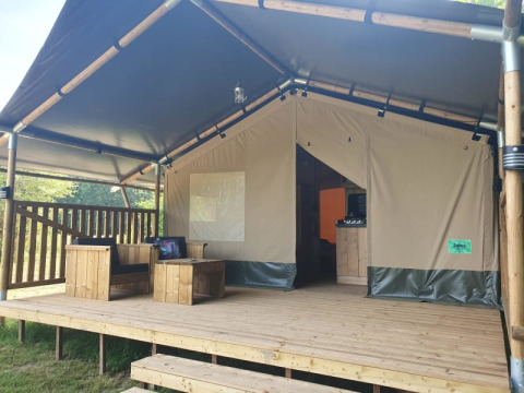 Safarizelt mit Holzterrasse und Sitzmöbeln im Moulin du Pommier Glamping & Camping in Frankreich.