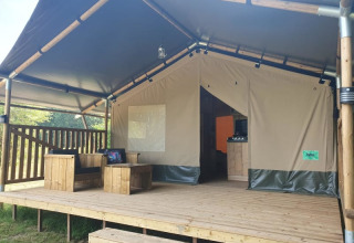 Tienda safari con terraza de madera y muebles en Moulin du Pommier Glamping & Camping en Francia.