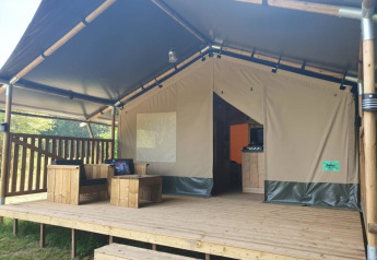 Safarizelt mit Holzterrasse und Sitzmöbeln im Moulin du Pommier Glamping & Camping in Frankreich.