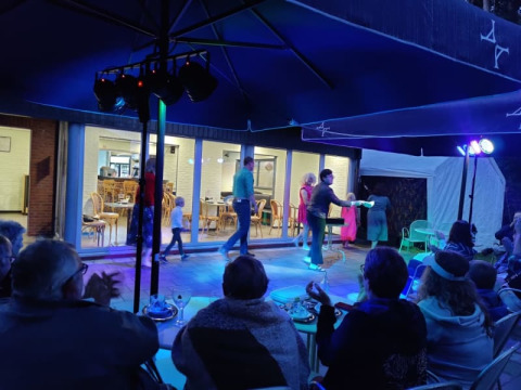 Espectáculo nocturno al aire libre en la carpa Safari de Camping het Swinnenbos en Bélgica, con público y luces.