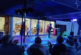 Espectáculo nocturno al aire libre en la carpa Safari de Camping het Swinnenbos en Bélgica, con público y luces.