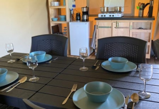 Comedor y cocina en tienda safari en Camping Sonnenberg, Alemania, mesa puesta para cuatro personas.