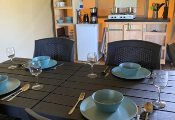 Zona pranzo e cucina in tenda safari al Camping Sonnenberg, Germania, tavola apparecchiata per quattro.