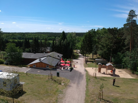 Aerial view of the Safari tent at Camping Sonnenberg in Germany, surrounded by forest, playground and blue sky.
